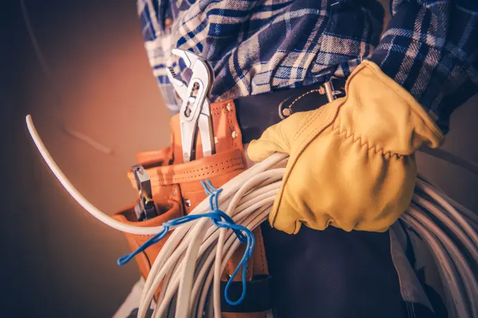 Zoom sur un électricien Assemtech avec son équipement à la main et à le ceinture